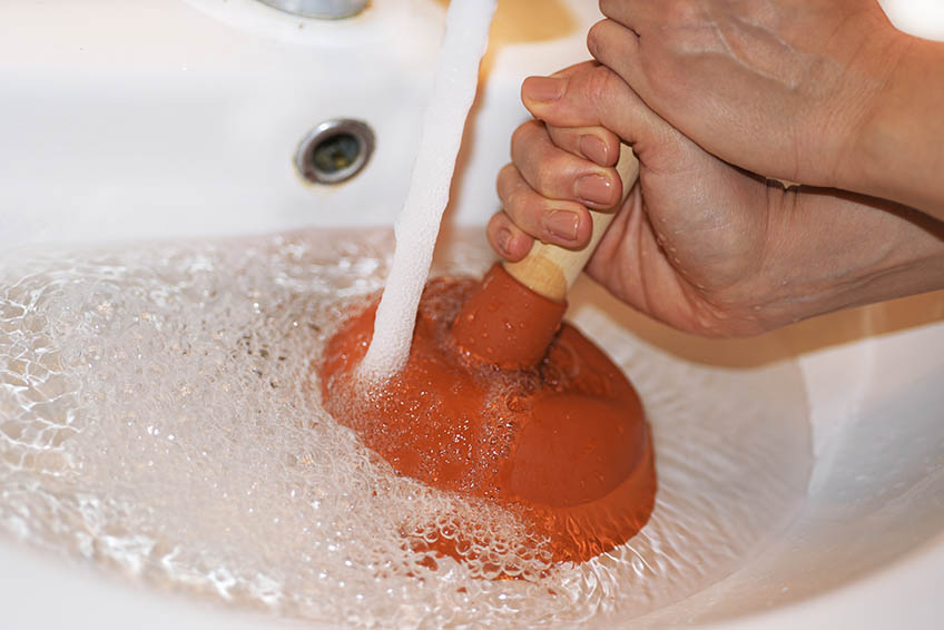 Woman with  plunger trying to remove clogged sinks. Abstract photo.